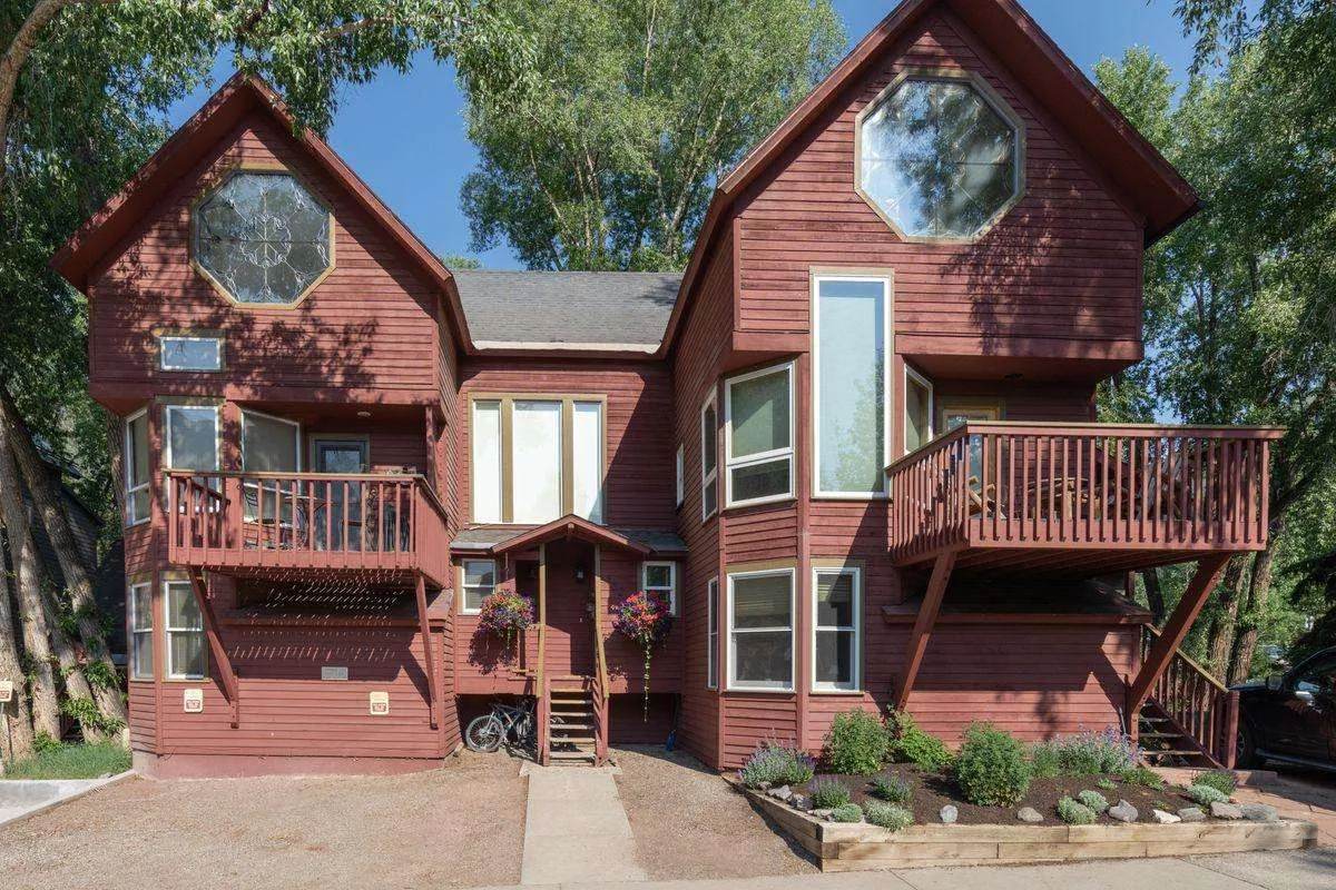 This photo highlights the property’s unique architectural style, with balconies and a landscaped garden in the foreground. The inviting outdoor spaces suggest areas to relax or enjoy a morning coffee before heading into town, while also hinting at the home’s close connection to the outdoors.