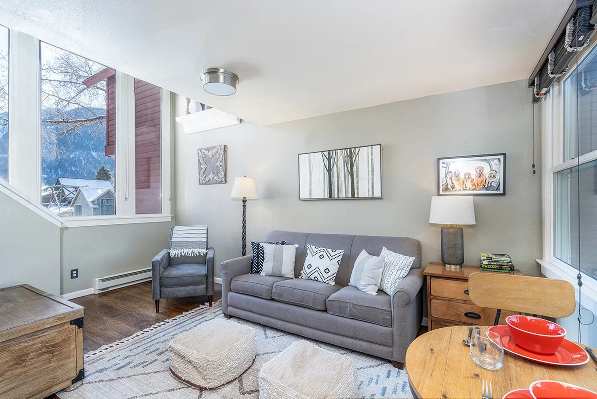 The image showcases a stylish, inviting living area with a plush sofa, eye-catching decorative art, and a modern dining table—all set within a cozy, well-lit space. The arrangement suggests an atmosphere perfect for unwinding after a day of adventure or gathering for intimate meals.